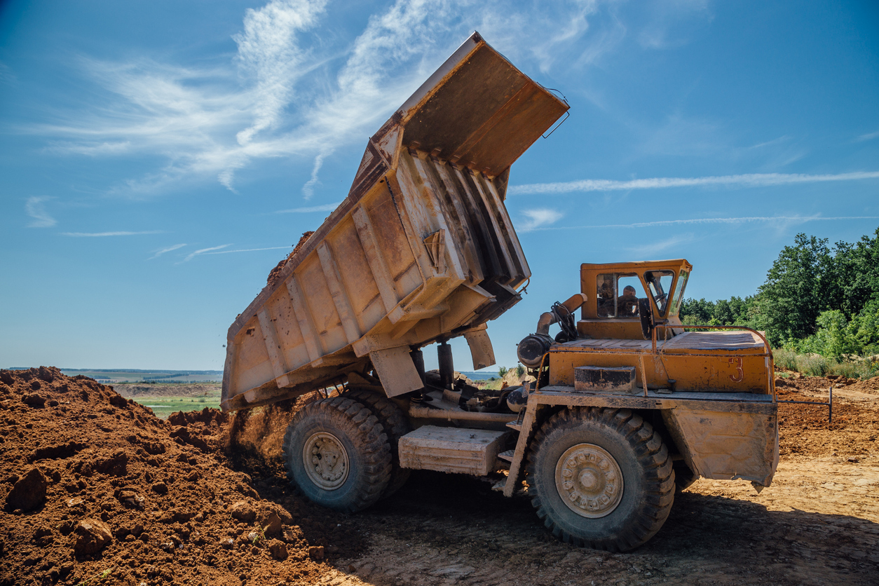 Dump truck unloads soil with crushed stone.