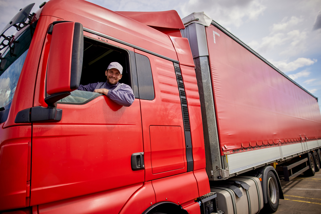 Portrait of a male truck driver sitting inside the big red truck.