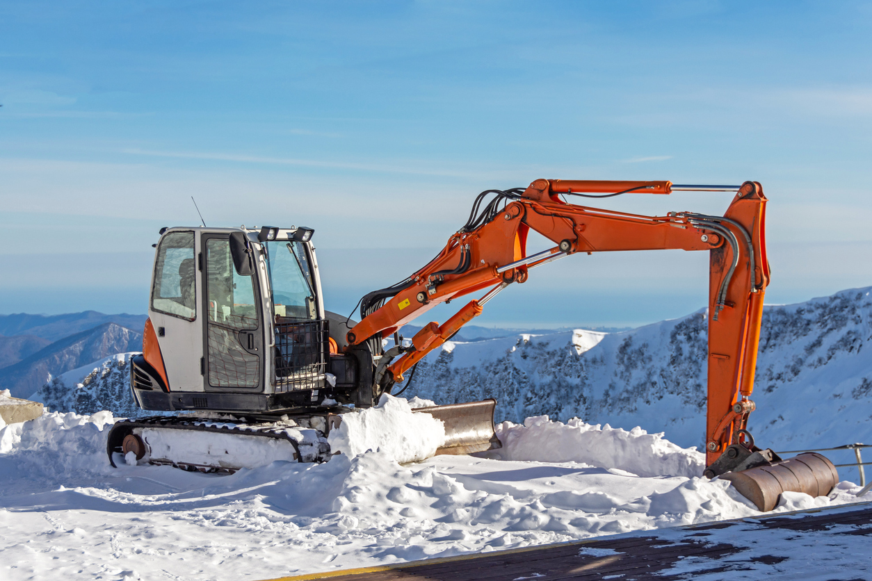 Excavator to clear snow on top of snow mountain ski resort.